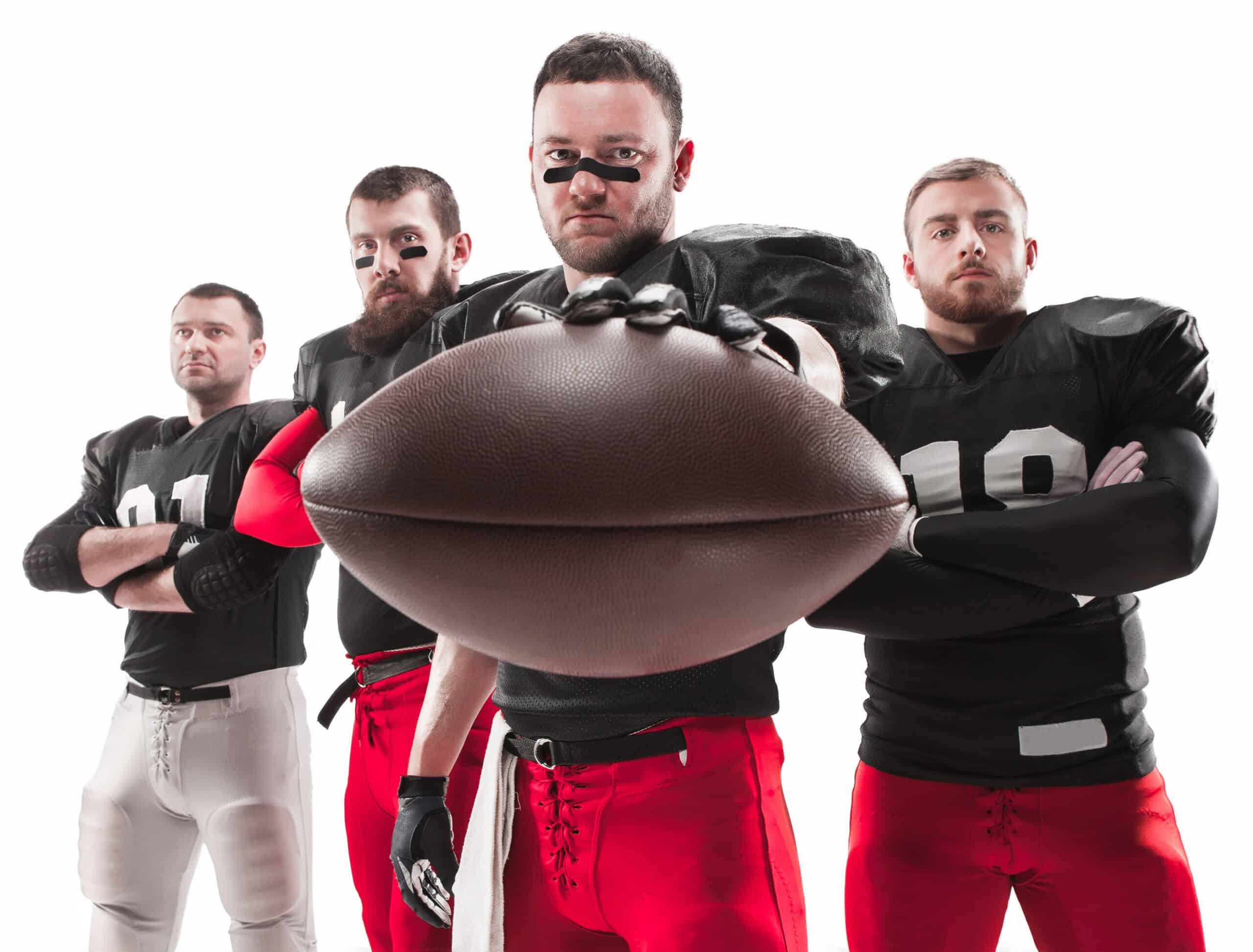 The four american football players posing with ball on white background